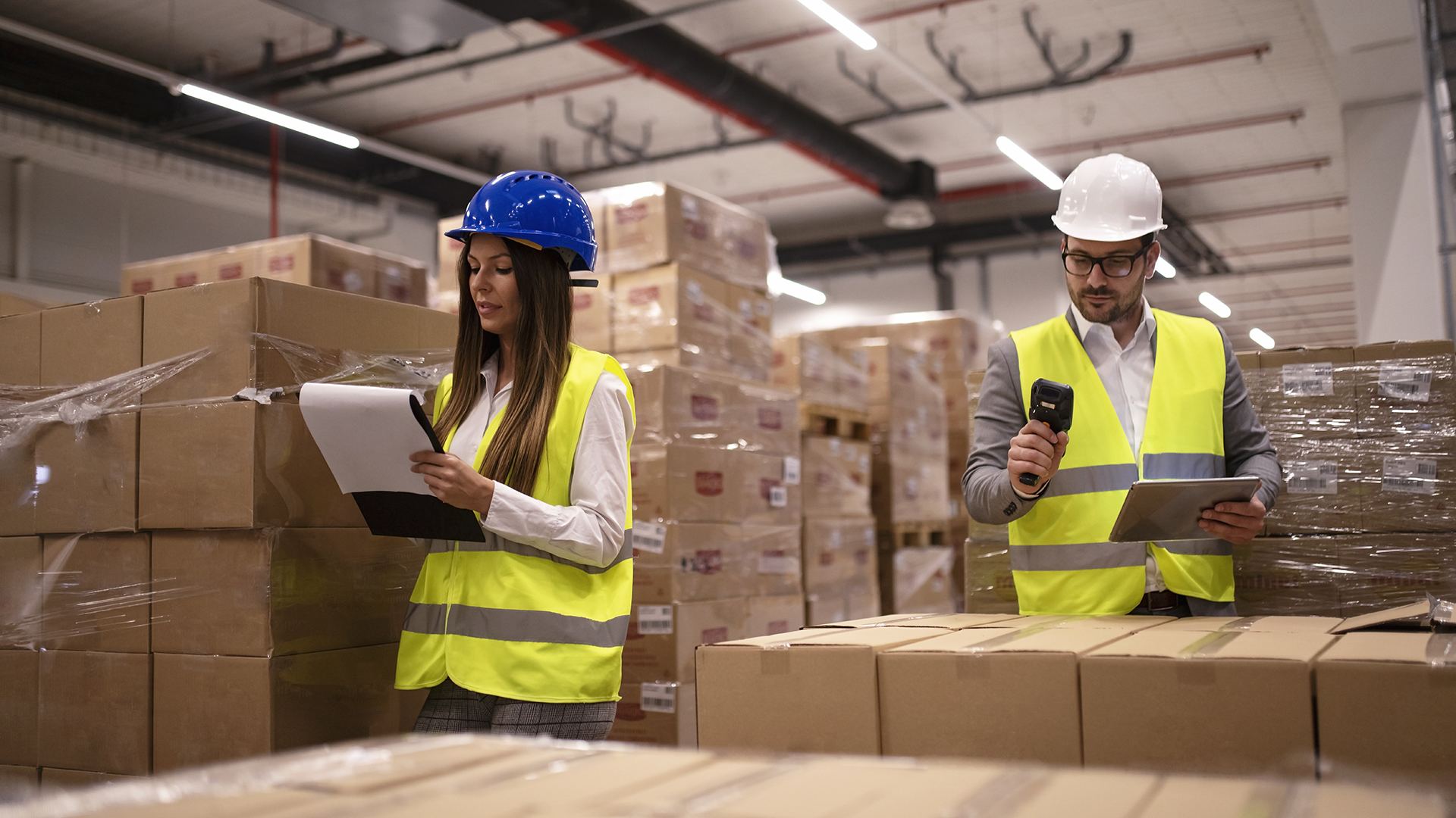 Warehouse workers using bar code scanner and tablet and checking goods inventory.
